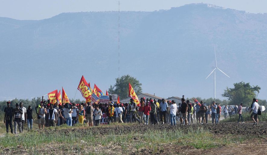 African migrant workers stage a march to protest against their work conditions, following the death of 16 of their colleagues in two separate road accidents, near Foggia, Italy, Wednesday, Aug. 8, 2018. Several hundred of tomatoes fruit pickers marched from the shanty town of San Severo to Foggia as an Italian labor union called for a national strike to raise awareness over the extremely poor working and housing conditions of immigrant farm workers in Italy. (Franco Cautillo/ANSA via AP)