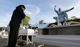 A woman prays in front of Peace Memorial Statue at Peace Park in Nagasaki, southern Japan, Thursday, Aug. 9, 2018, marking the 73rd anniversary of U.S. bombing on the city. (Takuma Kaneko/Kyodo News via AP)