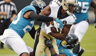 New Orleans Saints wide receiver Michael Thomas (13) is stopped after a reception by Jacksonville Jaguars cornerback Jalen Ramsey, left, and defensive back Tashaun Gipson during the first half of an NFL preseason football game Thursday, Aug. 9, 2018, in Jacksonville, Fla. (AP Photo/Stephen B. Morton)