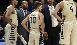 This photo from Nov. 28, 2017, shows Wake Forest assistant coach Jamill Jones, second from left, with the team and head coach Danny Manning, second from right, during the second half of an NCAA college basketball game in Winston-Salem, N.C. Police say Jones threw a punch that killed a New York City tourist who knocked on his car window thinking it was his Uber ride. He was arrested Thursday, Aug. 9, 2018, and charged with assault. (AP Photo/Chuck Burton)