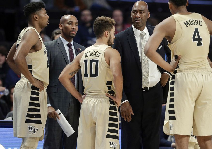 This photo from Nov. 28, 2017, shows Wake Forest assistant coach Jamill Jones, second from left, with the team and head coach Danny Manning, second from right, during the second half of an NCAA college basketball game in Winston-Salem, N.C. Police say Jones threw a punch that killed a New York City tourist who knocked on his car window thinking it was his Uber ride. He was arrested Thursday, Aug. 9, 2018, and charged with assault. (AP Photo/Chuck Burton)