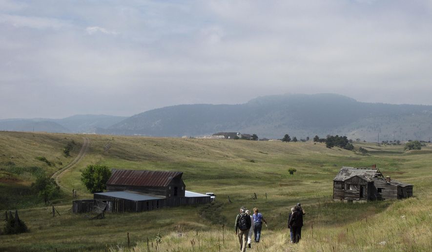 FILE - In this Aug. 11, 2017 file photo, visitors approach a former ranch house and barn during a guided hike on the Rocky Flats National Wildlife Refuge near Denver. The refuge is on land that was a buffer zone around a former nuclear weapons plant. On Thursday, Aug. 9, 2018, a judge turned down a request to keep the refuge closed to the public while the courts hear a lawsuit claiming the federal government has not studied the site's safety closely enough. (AP Photo/Dan Elliott, File)