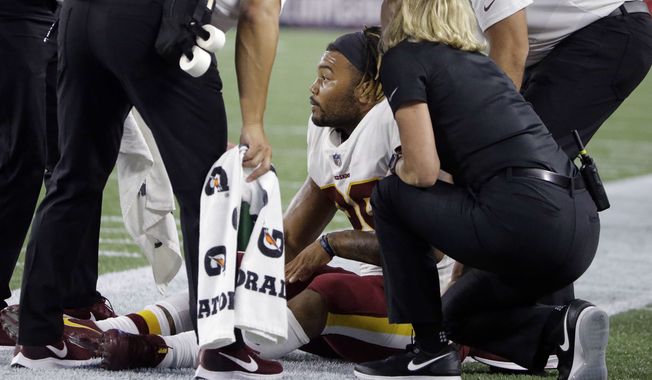 Washington Redskins running back Derrius Guice, center, receives attention on the field after an injury during the first half of a preseason NFL football game against the New England Patriots, Thursday, Aug. 9, 2018, in Foxborough, Mass. (AP Photo/Steven Senne)