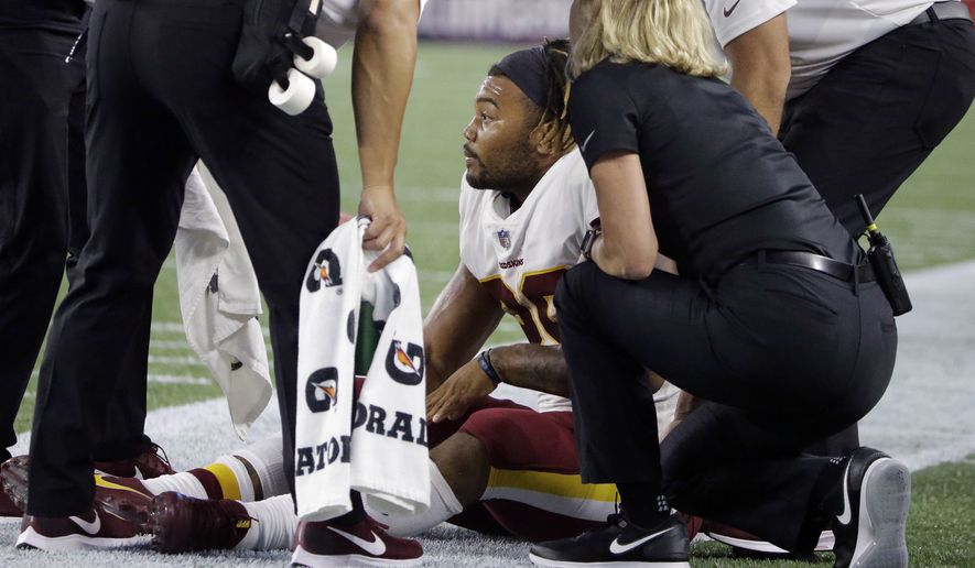 Washington Redskins running back Derrius Guice, center, receives attention on the field after an injury during the first half of a preseason NFL football game against the New England Patriots, Thursday, Aug. 9, 2018, in Foxborough, Mass. (AP Photo/Steven Senne)