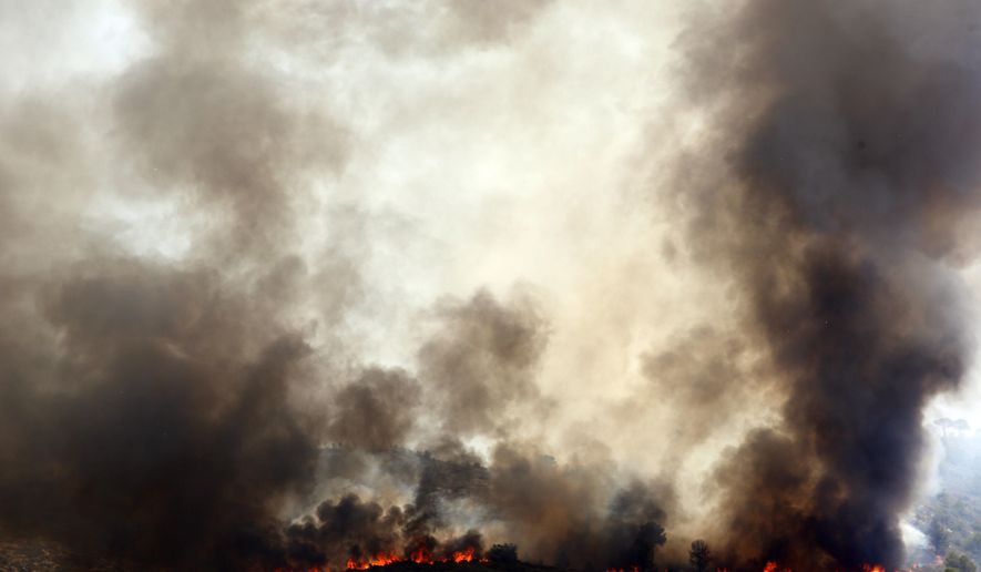 Spanish firefighters try to extinguish a wildfire in Pinet village, near Valencia Tuesday, Aug. 7, 2018. Spanish firefighters are still working to bring under control a forest blaze near Valencia. (AP Photo/Alberto Saiz)