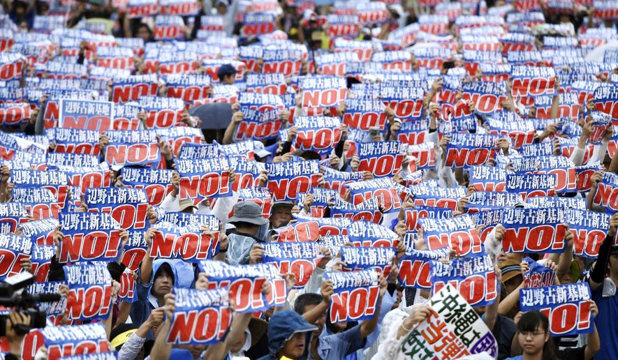 Protesters display signs against a planned U.S military base relocation during a rally in Naha, Okinawa prefecture, on the southern Japanese island Saturday, Aug. 11, 2018. (Koji Harada/Kyodo News via AP)