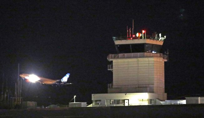 A plane flies past a control tower at Sea-Tac International Airport Friday evening, Aug. 10, 2018, in SeaTac, Wash. An airline mechanic stole an Alaska Airlines plane without any passengers and took off from Sea-Tac International Airport in Washington state on Friday night before crashing near Ketron Island, officials said. (AP Photo/Elaine Thompson)