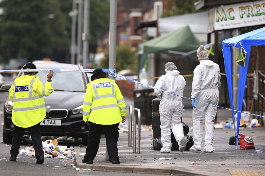 Forensic officers at the scene in the Moss Side area of Manchester, England, where several people have been injured after a shooting, early Sunday Aug. 12, 2018. Police in Manchester say 10 people have been hospitalized as the result of a shooting after a Caribbean carnival in the city. (Peter Byrne/PA via AP)