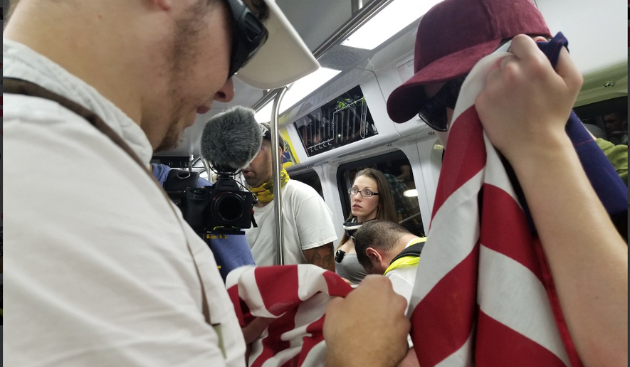 Attendees for a white nationalist rally in Washington, D.C., hold an American flag as they travel via a subway train from Vienna, Virginia, on Sunday. As many as 400 people were permitted to rally in the "Unite the Right 2" event marking the one-year anniversary of a violent gathering in Charlottesville, Virginia. Photo by Julia Airey / The Washington Times