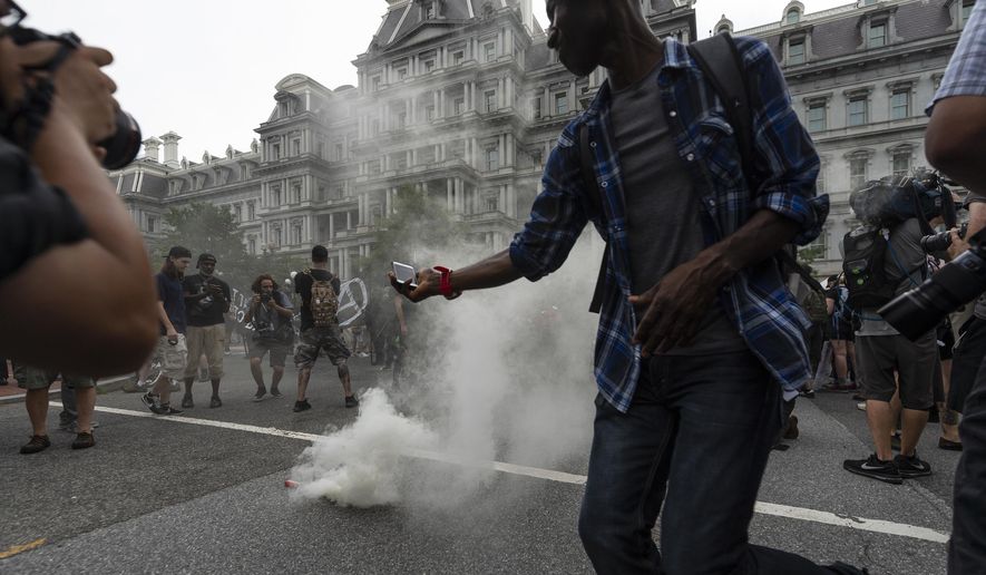 Journalists photograph a type of smoke grenade placed by antifa-activists in the middle of 17th street during the &amp;quot;Unite the Right 2&amp;quot; rally in Washington, Sunday, Aug. 12, 2018. (Craig Hudson/Charleston Gazette-Mail via AP) ** FILE **