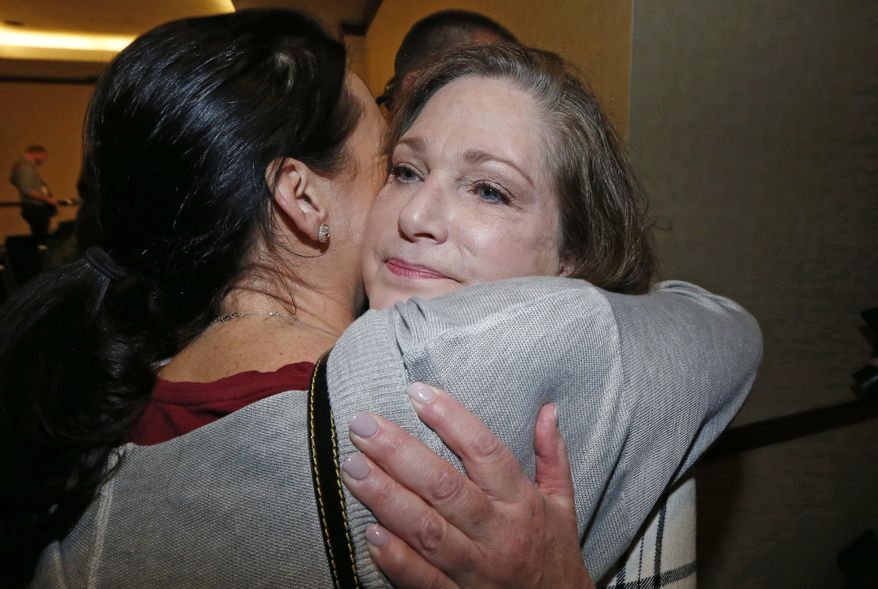 FILE - In this April 5, 2018, file photo, plaintiff McKenna Denson, right, receives a hug from supporter Jenea Gillespie, left, after speaking with reporters during a news conference in Salt Lake City. A judge is refusing to dismiss a lawsuit claiming Denson was raped after the Mormon church allowed a man to oversee young missionaries in the 1980s despite a history of sexual misconduct. Her attorney says the Monday, August 13, 2018, decision will allow them to investigate for other possible victims. (AP Photo/Rick Bowmer, File)