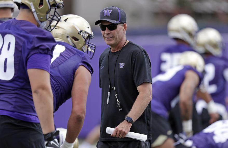 File- This Aug. 3, 2018, file photo shows Washington head coach Chris Petersen walking on the field during a team football practice in Seattle. Petersen’s Huskies are the preseason favorites to win the Pac-12 with their roster full of NFL-caliber talent, but the entire league is looking for an improved season after going 1-8 in bowl games last winter. (AP Photo/Elaine Thompson, File)