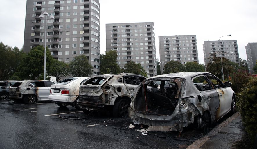 Burned cars parked at Frolunda Square in Gothenburg, Tuesday, Aug. 14, 2018. Masked youth torched dozens of cars overnight in Sweden and threw rocks at police, prompting an angry response from the prime minister, who on Tuesday spoke of an "extremely organized" night of vandalism. (Adam Ihse/TT via AP)