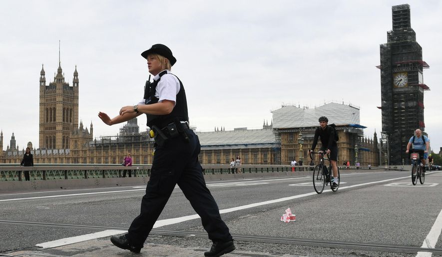 A police woman patrols on Westminster Bridge after a car crashed into security barriers outside the Houses of Parliament, in London, Tuesday, Aug. 14, 2018. London police say that a car has crashed into barriers outside the Houses of Parliament and that there are a number of injured. (Stefan Rousseau/PA via AP)