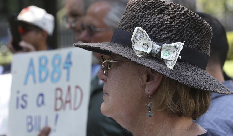 With a dollar bill stuck in her hat, Donna Poulos, of Los Altos, joined other open-government supporters rallying against a measure that would let legislative leaders raise and spend more money to help their preferred candidates, Tuesday, Aug. 14, 2018, in Sacramento, Calif. The bill AB84 by Assemblyman Kevin Mullin, D-South San Francisco, was approved by a state Senate Committee. (AP Photo/Rich Pedroncelli)