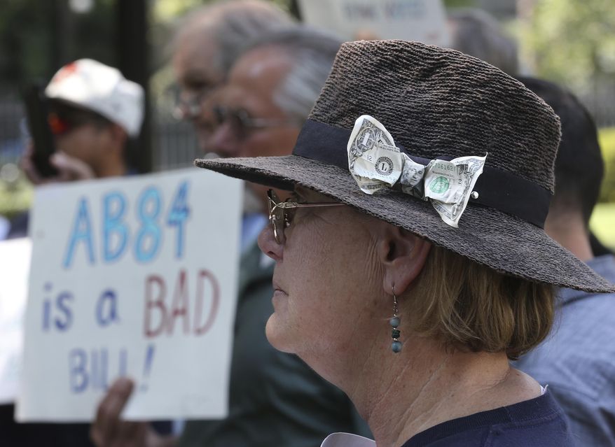 With a dollar bill stuck in her hat, Donna Poulos, of Los Altos, joined other open-government supporters rallying against a measure that would let legislative leaders raise and spend more money to help their preferred candidates, Tuesday, Aug. 14, 2018, in Sacramento, Calif. The bill AB84 by Assemblyman Kevin Mullin, D-South San Francisco, was approved by a state Senate Committee. (AP Photo/Rich Pedroncelli)