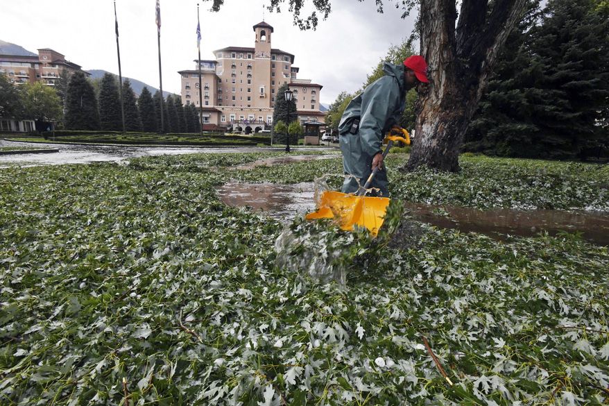 FILE - In this Aug. 6, 2018 file photo, Carlton Burton, an employee of the Broadmoor Hotel, shovels leaves and hail after a storm that damaged buildings, injured 14 people and killed at least five zoo animals in the Colorado Springs, Colo., area. Hailstorms inflict billions of dollars in damage yearly in North America alone, and the cost will rise as the growing population builds more homes, offices and factories, climate and weather experts said Tuesday, Aug. 14. The role of climate change in hailstorms is harder to assess, the experts said at a conference at the National Center for Atmospheric Research in Boulder. (Jerilee Bennett/The Gazette via AP)