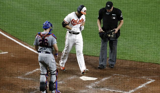 Baltimore Orioles&#x27; Chris Davis, center, crosses home plate in front of New York Mets catcher Kevin Plawecki, left, and umpire Jeff Nelson after rounding the bases on a solo home run in the seventh inning of a baseball game, Tuesday, Aug. 14, 2018, in Baltimore. (AP Photo/Patrick Semansky)