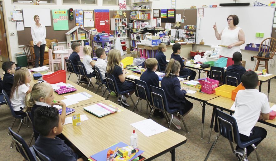 First-graders in Caryn Bednarek&#39;s class at Queen of All Saints Catholic School enjoy a snack and listen quietly as she goes over their new classroom procedures on the first day of the 2018-2019 school year Wednesday, Aug. 15, 2018, in Michigan City, Ind. (Kelley Smith/The News-Dispatch via AP) ** FILE **