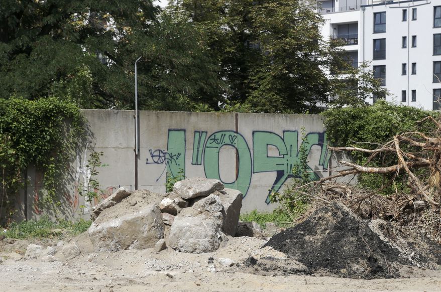 A newly discovered section of the Berlin Wall hides behind the bushes near the headquarters of Germany's Federal Intelligence Service in Berlin, Germany, Wednesday, Aug. 15, 2018. A local official has discovered a forgotten remnant of the Berlin Wall close to the new headquarters of Germany's foreign intelligence service. It's the second long-lost piece of the barrier to be identified and given protected status this year. (AP Photo/Miriam Karout)