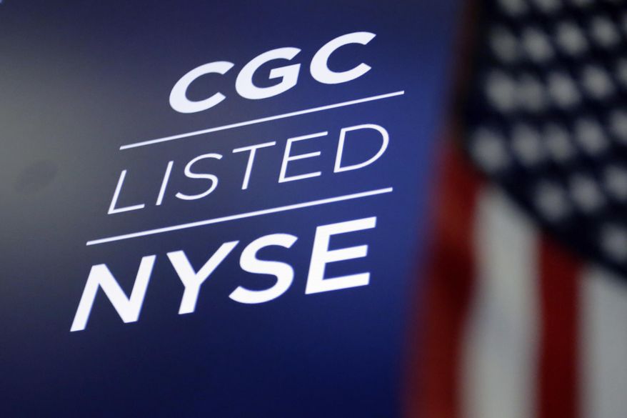 FILE- In this May 31, 2018, file photo the logo for Canada's Canopy Growth Corp. appears on a screen above a trading post on the floor of the New York Stock Exchange. The parent company of Corona beer and other alcoholic drinks is expanding its partnership with a Canadian pot producer, betting on the continued growth in the medical and recreational cannabis markets. Constellation Brands Inc. said Wednesday, Aug. 15, that it's buying 104.5 million shares worth $4 billion in Canopy Growth Corp. (AP Photo/Richard Drew, File)