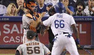Los Angeles Dodgers&#39; Yasiel Puig, right, shoves San Francisco Giants catcher Nick Hundley, left, as they argue while relief pitcher Tony Watson, below, runs in and home plate umpire Eric Cooper gets between them during the seventh inning of a baseball game, Tuesday, Aug. 14, 2018, in Los Angeles. (AP Photo/Mark J. Terrill)