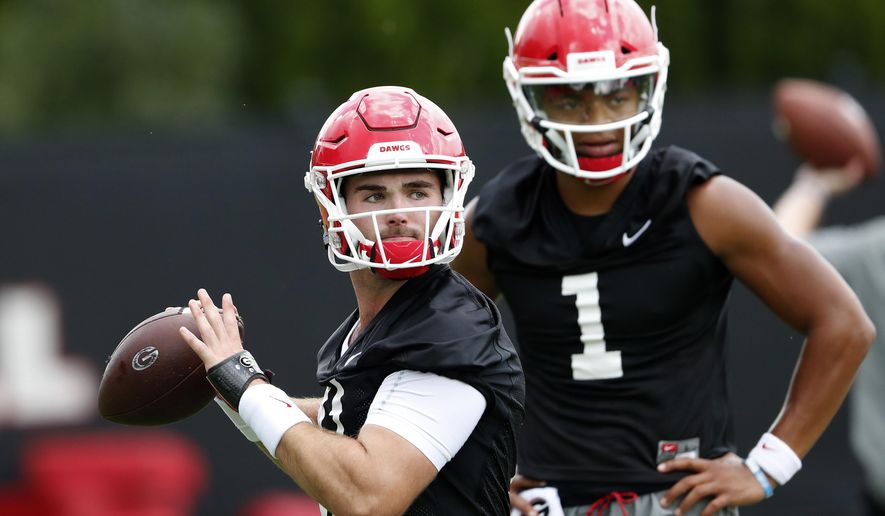 File-This Aug. 3, 2018, file photo shows Georgia quarterback Jake Fromm (11) throwing a pass as freshman quarterback Justin Fields (1) looks on during their NCAA college football training camp practice in Athens, Ga. Fields is competing with Fromm, whose composure as a freshman starter in 2017 was a big key in the Bulldogs winning their first Southeastern Conference championship since 2005 and advancing to the national championship game. In each of the last two years, the new kid won the starting job after only one game. (AP Photo/John Bazemore, File)