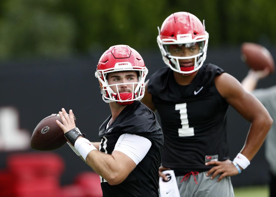 File-This Aug. 3, 2018, file photo shows Georgia quarterback Jake Fromm (11) throwing a pass as freshman quarterback Justin Fields (1) looks on during their NCAA college football training camp practice in Athens, Ga. Fields is competing with Fromm, whose composure as a freshman starter in 2017 was a big key in the Bulldogs winning their first Southeastern Conference championship since 2005 and advancing to the national championship game. In each of the last two years, the new kid won the starting job after only one game. (AP Photo/John Bazemore, File)