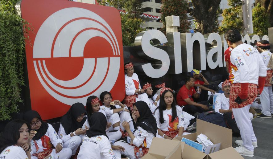 In this Aug. 5, 2018, photo, students sit in front of building that houses the headquarters of Sinarmas Group, one of Indonesia's largest palm oil company, in Jakarta, Indonesia. The main global group for certifying sustainable wood has suspended plans to give its influential endorsement to Indonesian paper giant Sinarmas after revelations it cut down tropical forests and used an opaque corporate structure to hide its activities. (AP Photo/Tatan Syuflana)