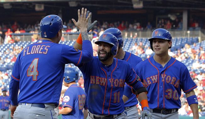 New York Mets&#x27; Jose Bautista, center, high-fives Wilmer Flores after Bautista hit a grand slam during the fifth inning of a baseball game against the Philadelphia Phillies, Thursday, Aug. 16, 2018, in Philadelphia. (AP Photo/Tom Mihalek)