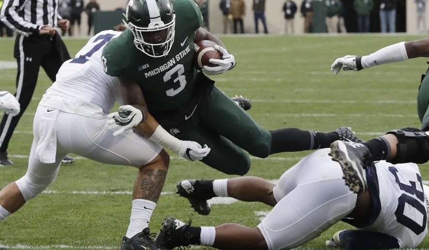 File- This Nov. 4, 2017, file photo shows Michigan State running back LJ Scott (3) being tackled by Penn State linebacker Koa Farmer, left, during the first half of an NCAA college football game in East Lansing, Mich. Scott enters his senior season with some impressive career rushing stats: 2,591 yards and 25 touchdowns. A good final season could put him in the top four on the school’s career list in both categories but he also has room for improvement. He was part of a team-wide fumbling problem that plagued the Spartans last year.(AP Photo/Carlos Osorio, File)