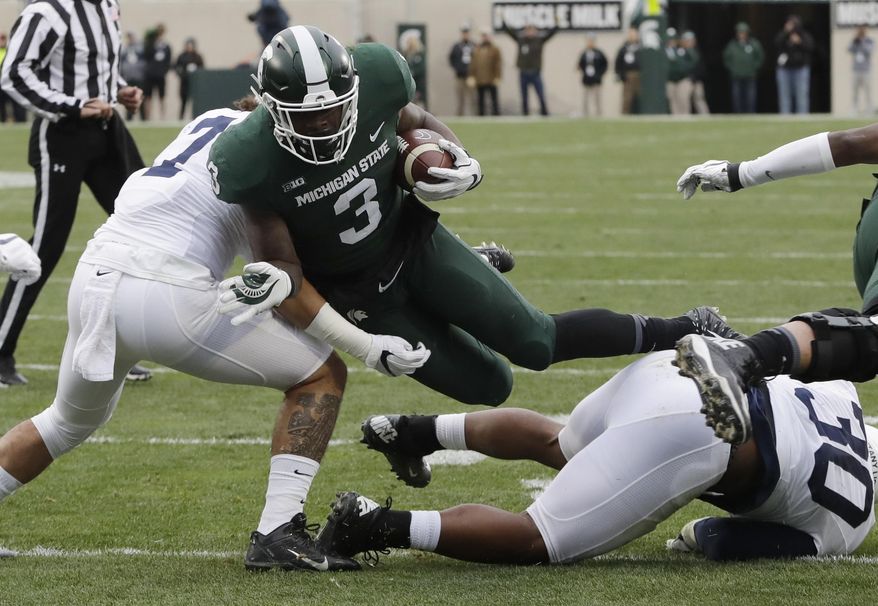 File- This Nov. 4, 2017, file photo shows Michigan State running back LJ Scott (3) being tackled by Penn State linebacker Koa Farmer, left, during the first half of an NCAA college football game in East Lansing, Mich. Scott enters his senior season with some impressive career rushing stats: 2,591 yards and 25 touchdowns. A good final season could put him in the top four on the school’s career list in both categories but he also has room for improvement. He was part of a team-wide fumbling problem that plagued the Spartans last year.(AP Photo/Carlos Osorio, File)