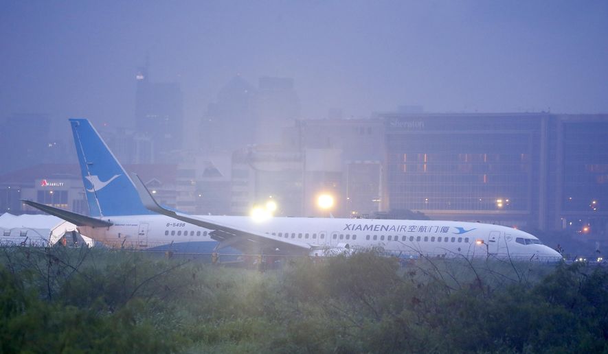 Rescuers are seen at the scene as a Boeing passenger plane from China, a Xiamen Air, lies on the grassy portion of the runway of the Ninoy Aquino International Airport after it skidded off the runway while landing Friday, Aug. 17, 2018 in suburban Pasay city southeast of Manila, Philippines. All the passengers and crew of Xiamen Air flight MF8667 were safe and were taken to an airport terminal, where they were given blankets and food before being taken to a hotel. (AP Photo/Bullit Marquez)