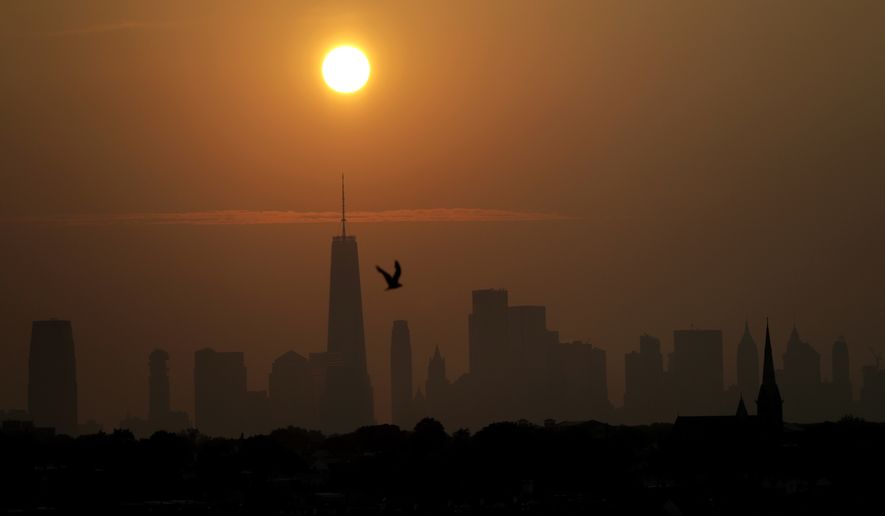 The sun rises behind the New York City skyline and moisture on a humid morning seen from Bayonne, N.J., Friday, Aug. 17, 2018. New York and the northern New Jersey region are expected to have a warm weekend with rain projected for Sunday. (AP Photo/Julio Cortez)
