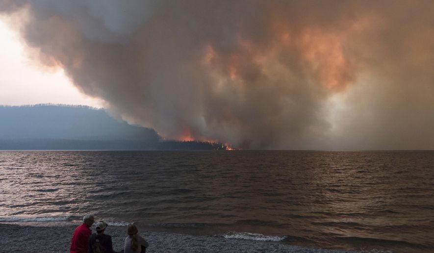 In this Sunday, Aug. 12, 2018, the Howe Ridge Fire burns at Glacier National Park, Mont. At least nine homes and cabins in a historic district of Glacier National Park have been destroyed in a wildfire that raged through the Montana park's busiest area and prompted the hasty evacuation of hundreds of visitors. Park officials said Tuesday, Aug. 14, 2018, that the lost buildings include the so-called Big House at Kelly's Camp, a resort developed early last century serving auto travelers along Glacier's famous Going-to-the-Sun Road. (Kristy Pancoast via AP)