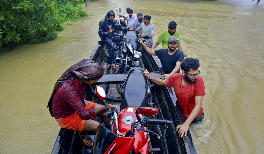 People salvage motorcycles in a country boat in a flooded area at Kainakary in Alappuzha district, Kerala state, India, Friday, Aug. 17, 2018. Rescuers used helicopters and boats on Friday to evacuate thousands of people stranded on their rooftops following unprecedented flooding in the southern Indian state of Kerala that killed more than 320 people in the past nine days, officials said. (AP Photo/Tibin Augustine)