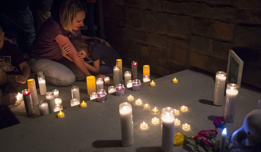 Jeanna Dietz hugs her daughter Eva, 7, while looking onto memorial on the front porch while others gather for a candle-lit vigil for Shanann Watts and her two daughters, Bella, 4, and Celeste, 3, in front of the Watts’ home on Friday, Aug. 17, 2018, in Frederick, Colo. Authorities are expected to file formal charges Monday against Christopher Watts, an oil and gas worker who authorities said dumped his wife and daughters&#x27; bodies on his employer&#x27;s property.  (Timothy Hurst/The Coloradoan via AP)