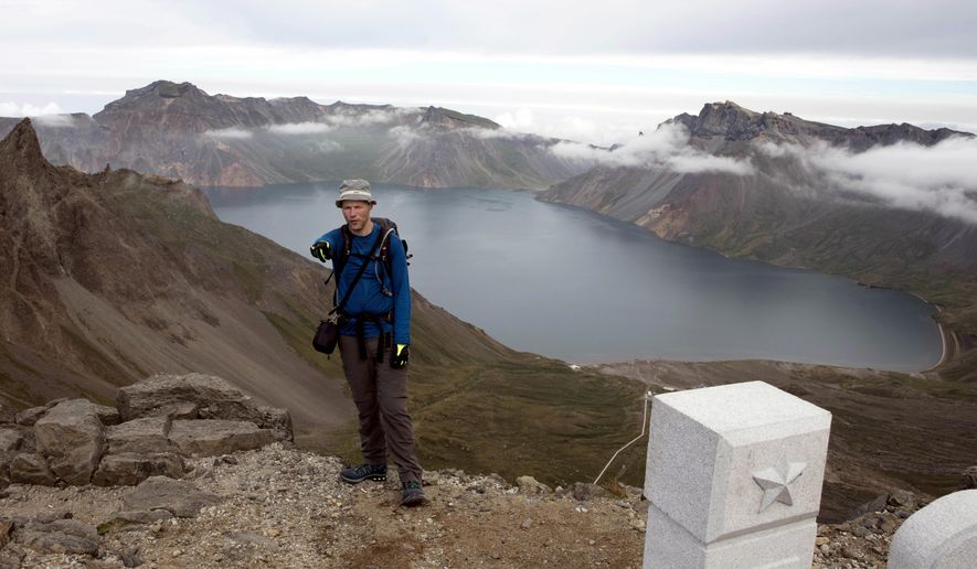 In this Saturday, Aug. 18,2018, photo, Tarjei Naess Skrede of Norway who is hiking with Roger Shepherd of Hike Korea stands near a view of the caldera and Lake Chon on Mount Paektu in North Korea. Hoping to open up a side of North Korea rarely seen by outsiders, Shepherd, a New Zealander who has extensive experience climbing the mountains of North and South Korea is leading the first group of foreign tourists allowed to trek off road and camp out under the stars on Mount Paektu, a huge volcano that straddles the border that separates China and North Korea. (AP Photo/Ng Han Guan)