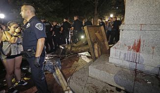 Police stand guard after the confederate statue known as Silent Sam was toppled by protesters on campus at the University of North Carolina in Chapel Hill, N.C., Monday, Aug. 20, 2018. (AP Photo/Gerry Broome)