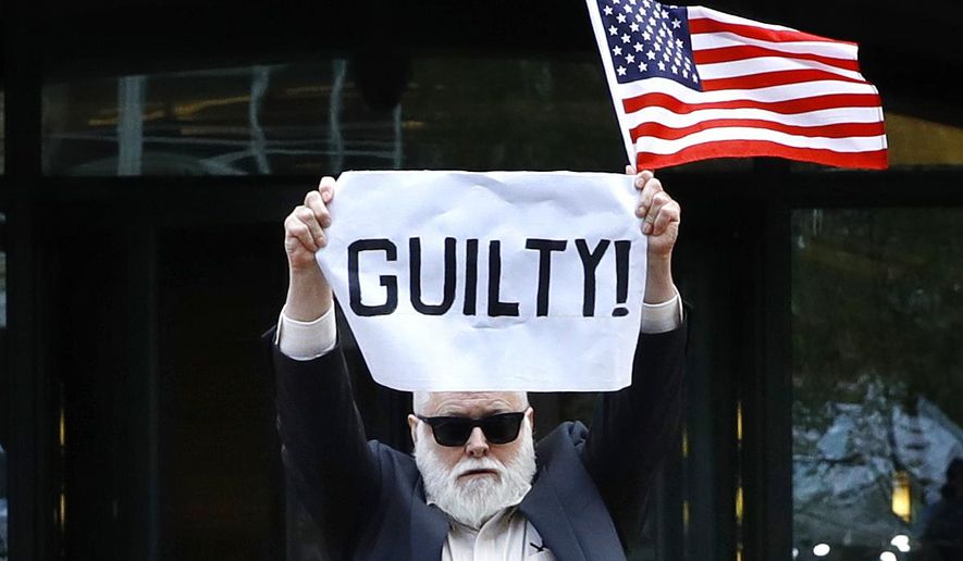 Protester Bill Christeson holds up a sign saying "guilty" as the first count of guilty comes in at he trial of former Donald Trump campaign chairman Paul Manafort, at federal court in Alexandria, Va., Tuesday, Aug. 21, 2018. (AP Photo/Jacquelyn Martin)