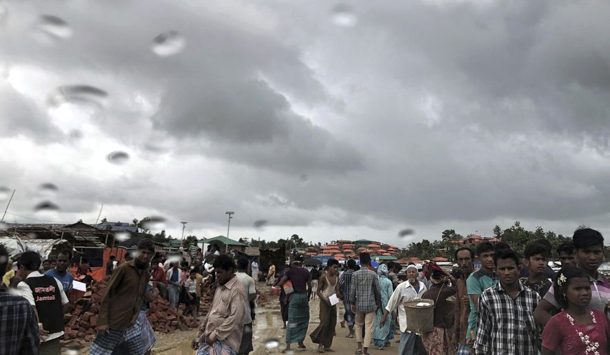 In this Tuesday, June 26, 2018, photo, Rohingya refugees walk on a muddy road in the rain through Jamtoli refugee camp in Bangladesh. For the hundreds of thousands of Rohingya children living in Bangladesh's refugee camps, dangers lurk everywhere: from malnutrition and disease to human traffickers to flooding and landslides. (AP Photo/Wong Maye-E)