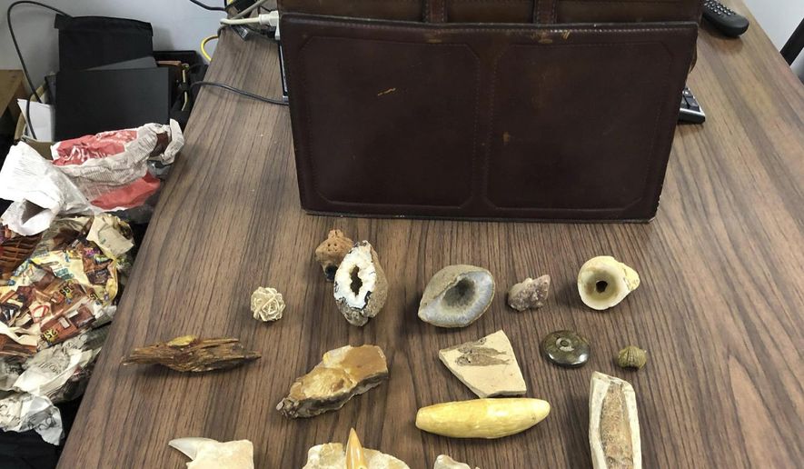 This undated photograph provided by the Mobile Police Department in Mobile, Ala., shows some of the contents of a briefcase that was found by a citizen and turned in to officers recently. Investigators are trying to locate the owner of the case, which included other items including what appeared to be ancient fossils. (Mobile Police Department via AP)