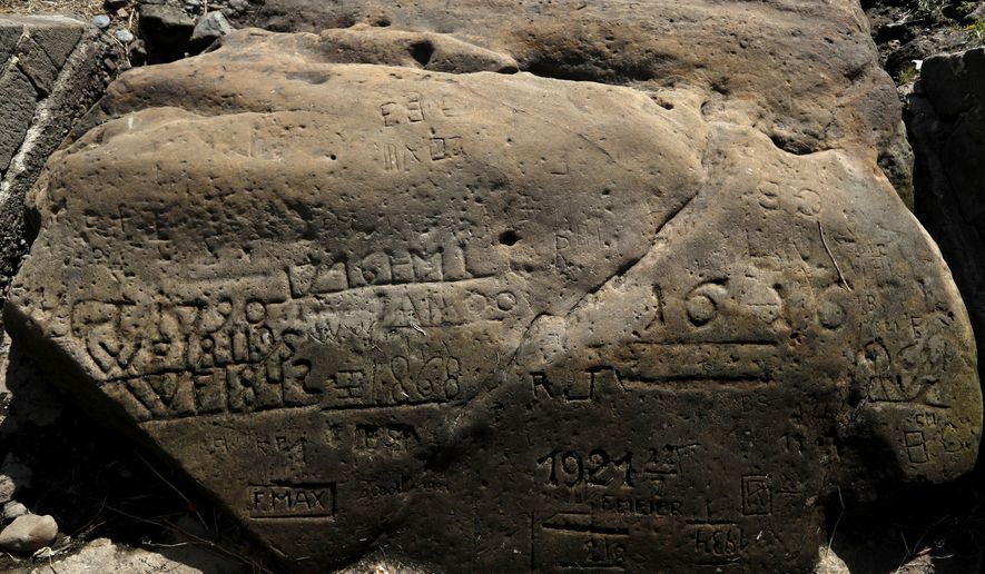 On of the so called "hunger stones" exposed by the low level of water in the Elbe river is seen in Decin, Czech Republic, Thursday, Aug. 23, 2018. The low level of water caused by the recent drought has exposed some stones at the river bed whose appearances in history meant for people to get ready for troubles. They are known as the "hunger stones" and they were chosen in the past to record low water levels. (AP Photo/Petr David Josek)