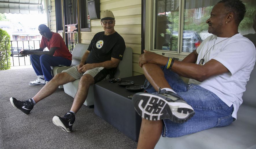 In a Friday, July 27, 2018 photo, veterans Hughs D. Walker Jr., left, Dave Matta, center, and Kenneth Williams talk on the porch of their "veteran rehabilitation home", which was started by former Probation Officer Dante Works, in Homewood, Pa. Works bought and renovated the home to assist veterans who are in the last process of "graduating" from Veterans Court in hopes that it would be a safe and comfortable environment for men to stay while getting back on their feet. (Jessie Wardarski/Pittsburgh Post-Gazette via AP)