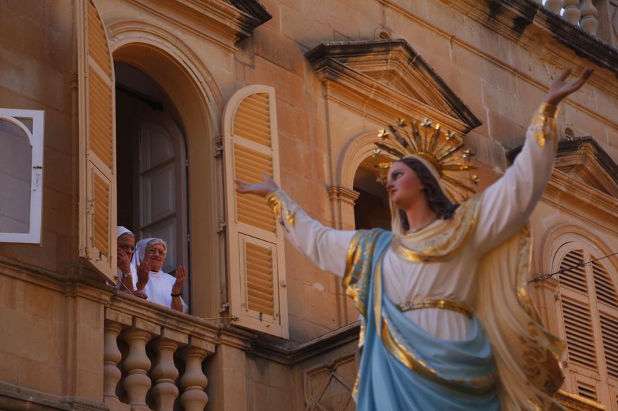 In this file photo taken on Wednesday, Aug. 15, 2018, nuns offer a prayer as the statue of the Virgin Mary being carried through the streets of Rabat on the island of Gozo in the Maltese archipelago, during the feast day of the Assumption of Mary. (AP Photo/Niranjan Shrestha) ** FILE **