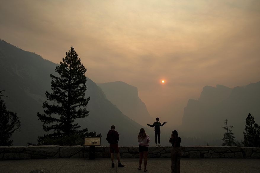 FILE - In this July 25, 2018 file photo, Hannah Whyatt poses for a friend's photo as smoke from the Ferguson fire fills Yosemite Valley in Yosemite National Park, Calif. Alarmed by as much as $20 million in lost tourism revenue in July due to visitors' fear of wildfires, California tourism officials are teaming up with Oregon and Washington to reassure tourists they're safe to visit after deadly wildfires that have burned homes and clogged the air. (AP Photo/Noah Berger, File)