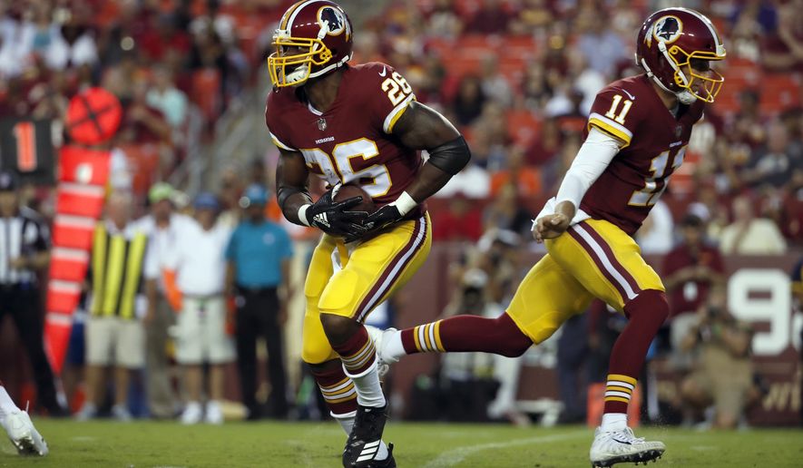 Washington Redskins running back Adrian Peterson (26) takes the handoff from Washington Redskins quarterback Alex Smith (11) during the first half of a preseason NFL football game against the Denver Broncos, Friday, Aug. 24, 2018, in Landover, Md. (AP Photo/Alex Brandon)