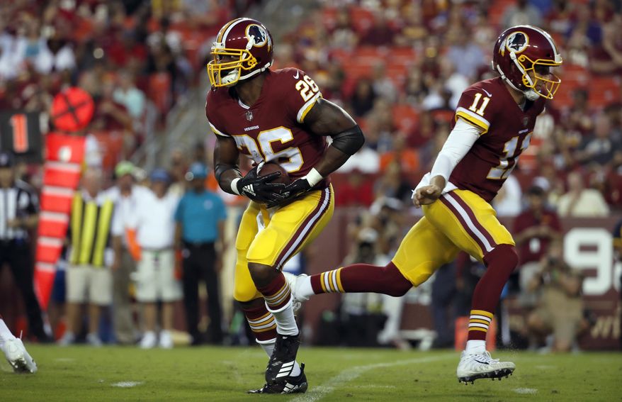Washington Redskins running back Adrian Peterson (26) takes the handoff from Washington Redskins quarterback Alex Smith (11) during the first half of a preseason NFL football game against the Denver Broncos, Friday, Aug. 24, 2018, in Landover, Md. (AP Photo/Alex Brandon)