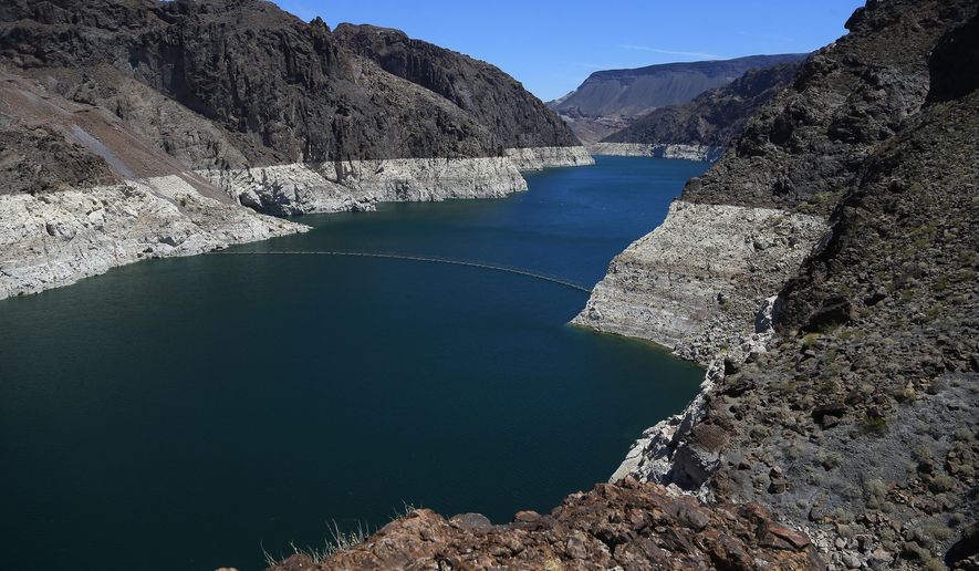 FILE - In this May 31, 2018, file photo, the low level of the water line is shown on the banks of the Colorado River in Hoover Dam, Ariz. U.S. officials say the chances of a shortage in the vital Colorado River system have risen to 57 percent in 2020. (AP Photo/Ross D. Franklin, File)