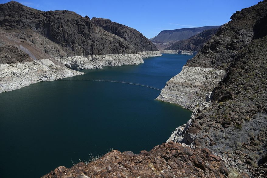 FILE - In this May 31, 2018, file photo, the low level of the water line is shown on the banks of the Colorado River in Hoover Dam, Ariz. U.S. officials say the chances of a shortage in the vital Colorado River system have risen to 57 percent in 2020. (AP Photo/Ross D. Franklin, File)